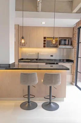 a kitchen with two bar stools in front of a counter at Brand New Premium Apartment with Large Balcony in Medellín
