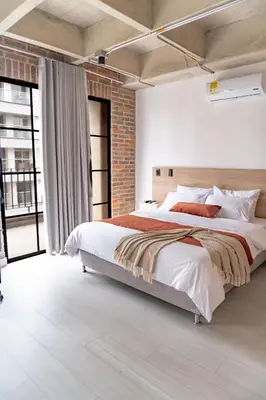 a bedroom with a large bed and a brick wall at Brand New Premium Apartment with Large Balcony in Medellín