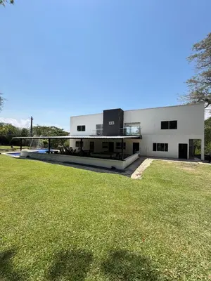 a large white building with a grass field in front of it at Finca Villa Sofía in Santa Fe de Antioquia