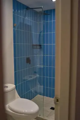 a blue tiled bathroom with a toilet and a shower at Casa en Laureles Estadio amplia y cómoda in Medellín