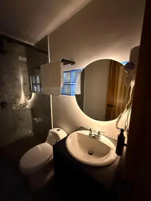 a bathroom with a sink and a toilet and a mirror at Villa Patio Colonial Santa Fe de Antioquia in Santa Fe de Antioquia