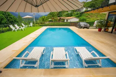 a swimming pool with two chairs and an umbrella at Casa Finca Moderna en Sopetran, Antioquia in Sopetran