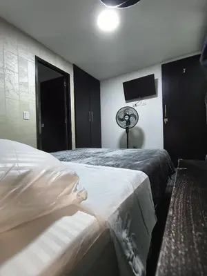 a bedroom with two beds and a flat screen tv at Hotel LAS MARIANA'S in Medellín