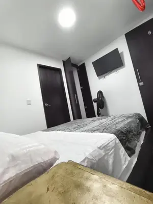 a bedroom with two beds and a flat screen tv at Hotel LAS MARIANA'S in Medellín