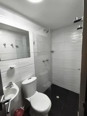 a white bathroom with a toilet and a sink at Hotel LAS MARIANA'S in Medellín