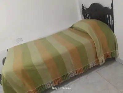 a bed with a green and orange blanket on it at Alojamiento Ríonegro in Rionegro