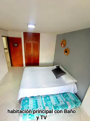 a bedroom with a large bed with white sheets at Guatape linda vista in Guatapé