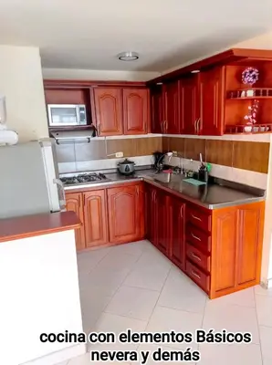a kitchen with wooden cabinets and a sink and a refrigerator at Guatape linda vista in Guatapé