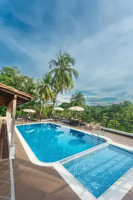 a pool at a resort with tables and umbrellas at Hotel Casa Encanto in Doradal