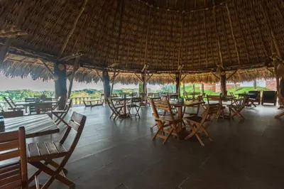 a restaurant with tables and chairs and a straw roof at Hotel Casa Encanto in Doradal