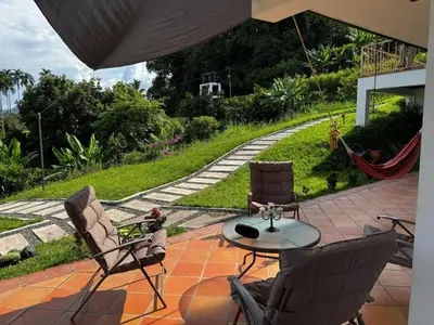 a patio with two chairs and a table and a hammock at Apto nuevo y moderno con piscina y bbq, zona rural in Anserma