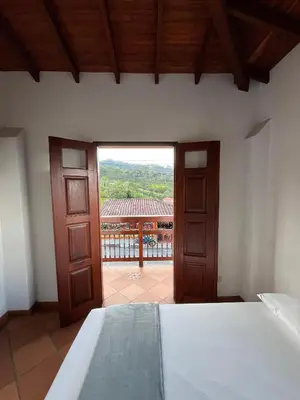 a bedroom with a bed and a view of a balcony at Hotel San Joaquin Jerico in Jericó