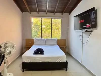 a bedroom with a bed with a flat screen tv at Apartaestudio en Laureles-plaza mayor-Av 33-laundry-wifi in Medellín