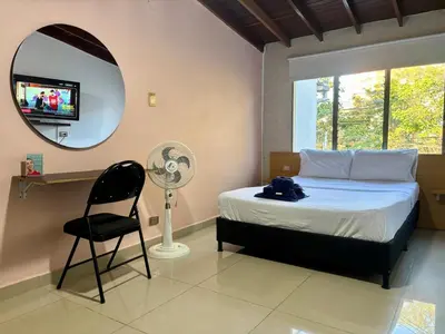 a bedroom with a bed and a chair and a mirror at Apartaestudio en Laureles-plaza mayor-Av 33-laundry-wifi in Medellín