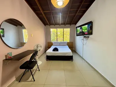 a bedroom with a bed and a tv on the wall at Apartaestudio en Laureles-plaza mayor-Av 33-laundry-wifi in Medellín