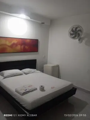 a bedroom with a white bed with a painting on the wall at Hotel eden centro in Medellín