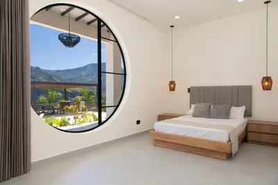 a bedroom with a large circular window and a bed at Villa with Pool, Jacuzzi, and Nature in Medellín