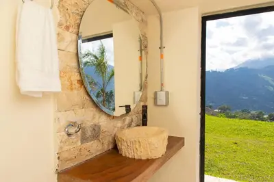 a bathroom with a round mirror and a stool at Villa with Pool, Jacuzzi, and Nature in Medellín