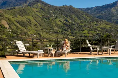 a woman sitting in a chair next to a swimming pool at Villa with Pool, Jacuzzi, and Nature in Medellín