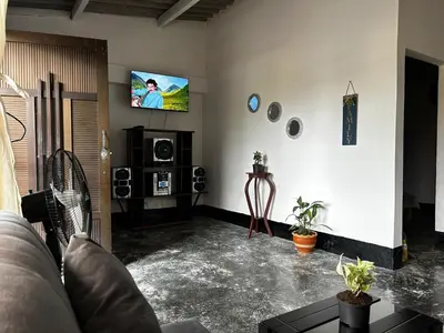 a living room with a couch and a tv on the wall at Casa Hotel Milagro de Abril in Mutatá