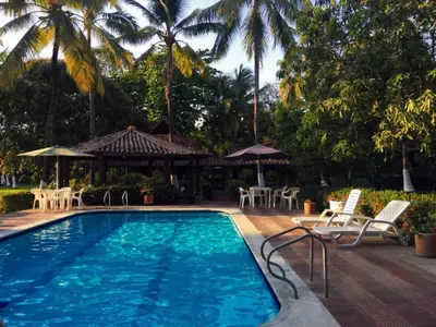 a pool with chairs and tables and palm trees at La Cornalina in Santa Fe de Antioquia