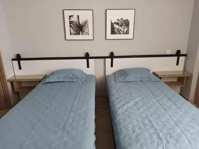 two beds in a bedroom with two pictures on the wall at Vibra en el corazón de Medellin! in Medellín