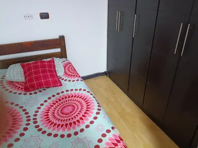 a bedroom with a bed with a red and white comforter at Ninfa del Mar Hostal Turístico in Manizales
