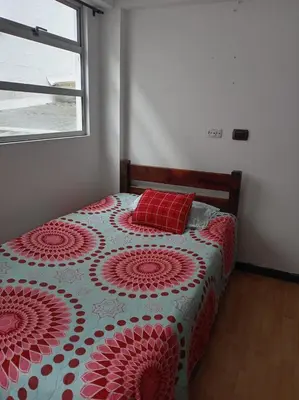 a bedroom with a bed with a red pillow and a window at Ninfa del Mar Hostal Turístico in Manizales