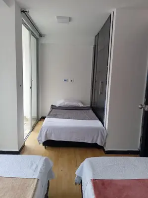 a bedroom with two beds and a large window at Ninfa del Mar Hostal Turístico in Manizales