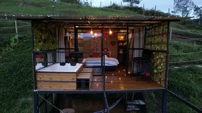 a small house with a bed and a deck at Glamping con vista de lujo in Guatapé