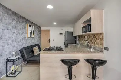 a kitchen with a counter and two black stools at 804- APTO 3BR a Pasos del Parque de Sabaneta in Sabaneta