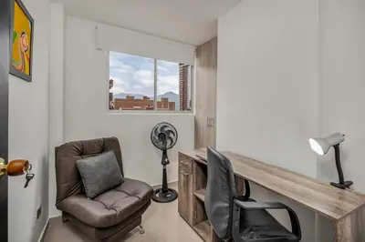 a room with a chair and a desk with a fan at 804- APTO 3BR a Pasos del Parque de Sabaneta in Sabaneta