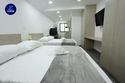 a hotel room with two beds with towels on the floor at Luzor Apartments in Medellín