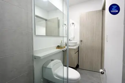 a bathroom with a toilet and a sink and a mirror at Luzor Apartments in Medellín