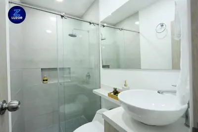 a bathroom with a glass shower and a sink at Luzor Apartments in Medellín