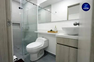 a bathroom with a toilet and a sink and a mirror at Luzor Apartments in Medellín
