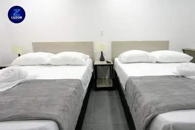two beds with white pillows in a hotel room at Luzor Apartments in Medellín