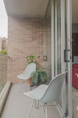 a balcony with white chairs and a brick wall at Luxury Studio El Poblado Pool Rooftop 4th Floor in Medellín