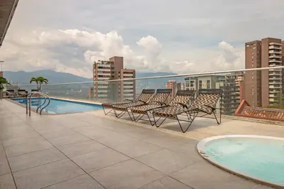 a balcony with chairs and a swimming pool on a building at Luxury Studio El Poblado Pool Rooftop 4th Floor in Medellín
