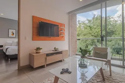 a living room with a tv and a table and a bed at Luxury Studio El Poblado Pool Rooftop 4th Floor in Medellín