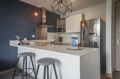 a kitchen with a counter with stools and a refrigerator at Luxury Studio El Poblado City View 7th Floor in Medellín