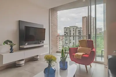 a living room with a tv and a red chair at Luxury Studio El Poblado City View 7th Floor in Medellín