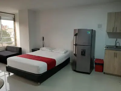 a bedroom with a large bed and a refrigerator at Amoblados la 70 Medellin 1 in Medellín
