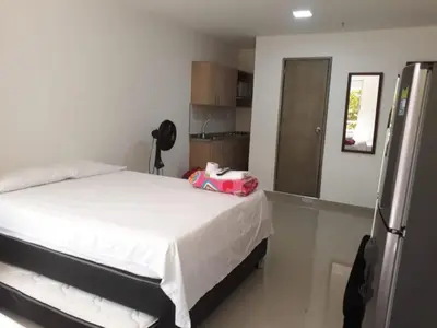 a bedroom with a white bed with a pink suitcase on it at Amoblados la 70 Medellin 1 in Medellín
