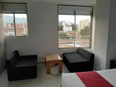a bedroom with a bed and a chair and window at Amoblados la 70 Medellin 1 in Medellín