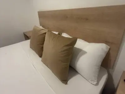 a bed with three pillows and a wooden headboard at Hotel, Villa Real,Medellín ,Laureles,Estadio in Medellín