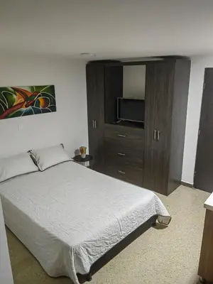 a bedroom with a bed and a cabinet with a television at Cozy studio in Conquistadores in Medellín
