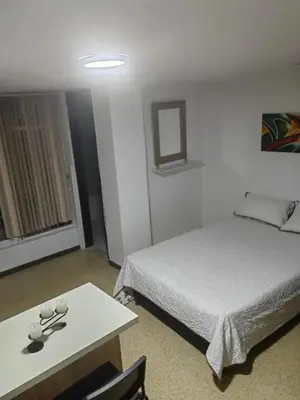 a hotel room with a bed and a table at Cozy studio in Conquistadores in Medellín