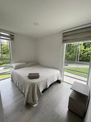 a bedroom with a bed and a large window at Moderno Apartamento Manizales in Manizales