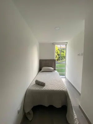 a bed in a white room with a window at Moderno Apartamento Manizales in Manizales